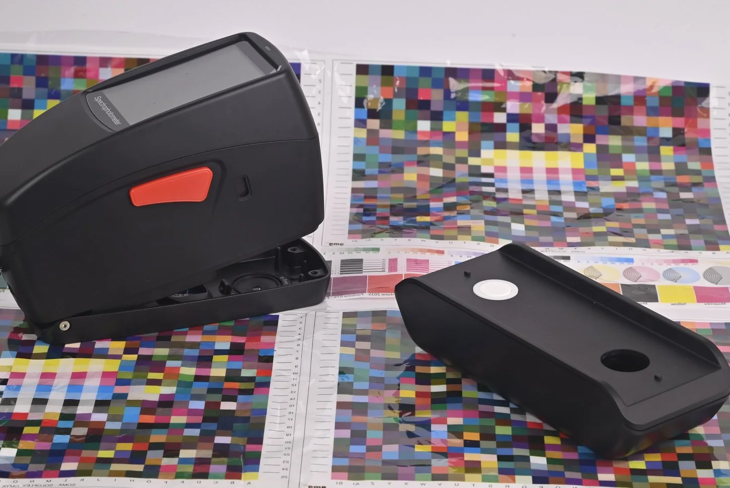 SpectroFit spectrodensitometer and its calibration base resting on printed CMYK colour charts